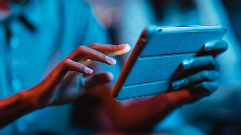 Hands holding a tablet, reading the news